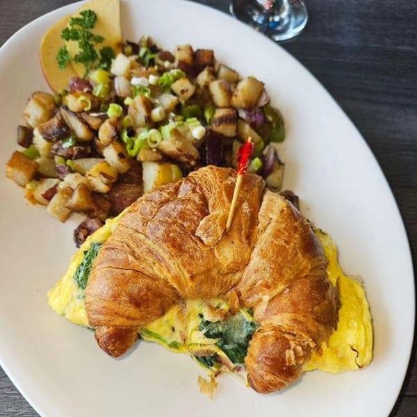 Hot Off the Griddle's croissant breakfast sandwich with eggs, spinach, and a side of home fries.