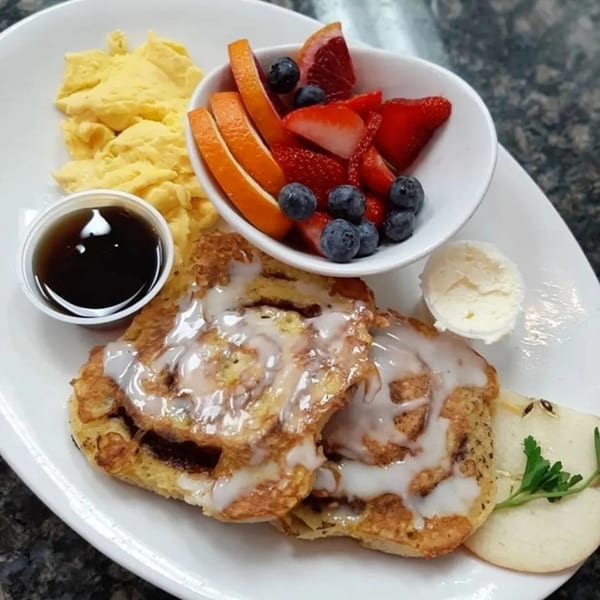 Hot Off the Griddle breakfast with cinnamon roll pancakes, scrambled eggs, fruit, and syrup.