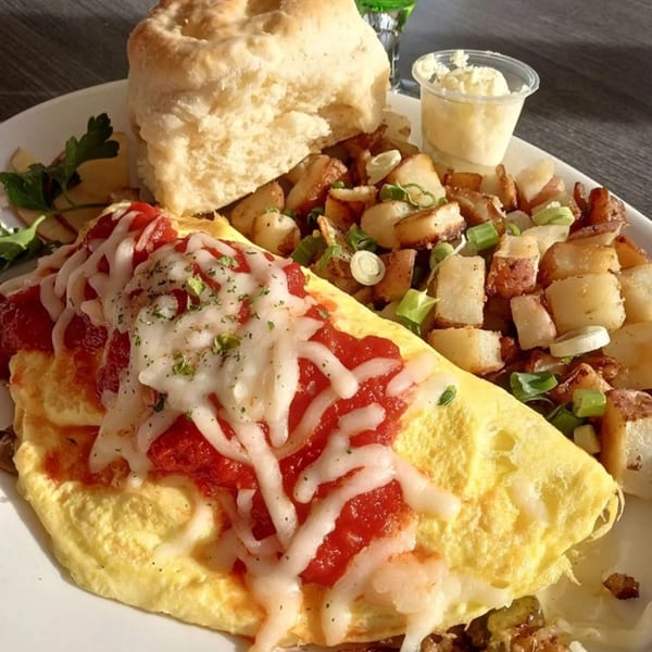 Omelet with red sauce and cheese, home fries, and a biscuit with butter from Hot Off the Griddle.